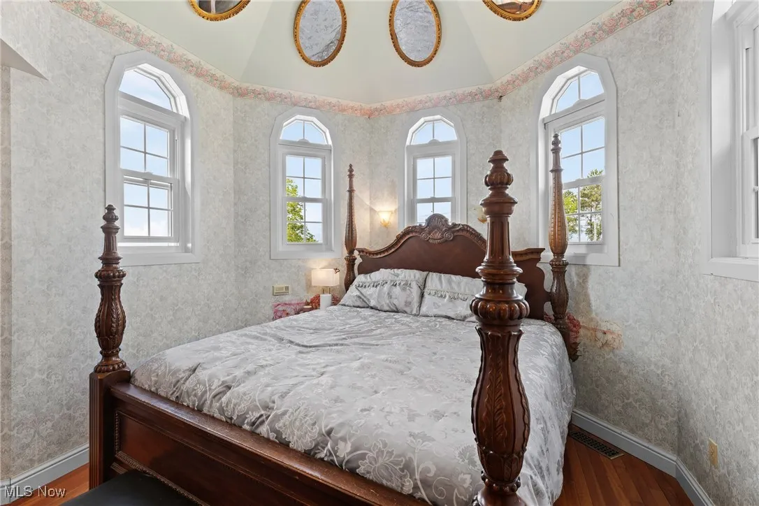 Bedroom featuring wood finished floors, baseboards, and wallpapered walls