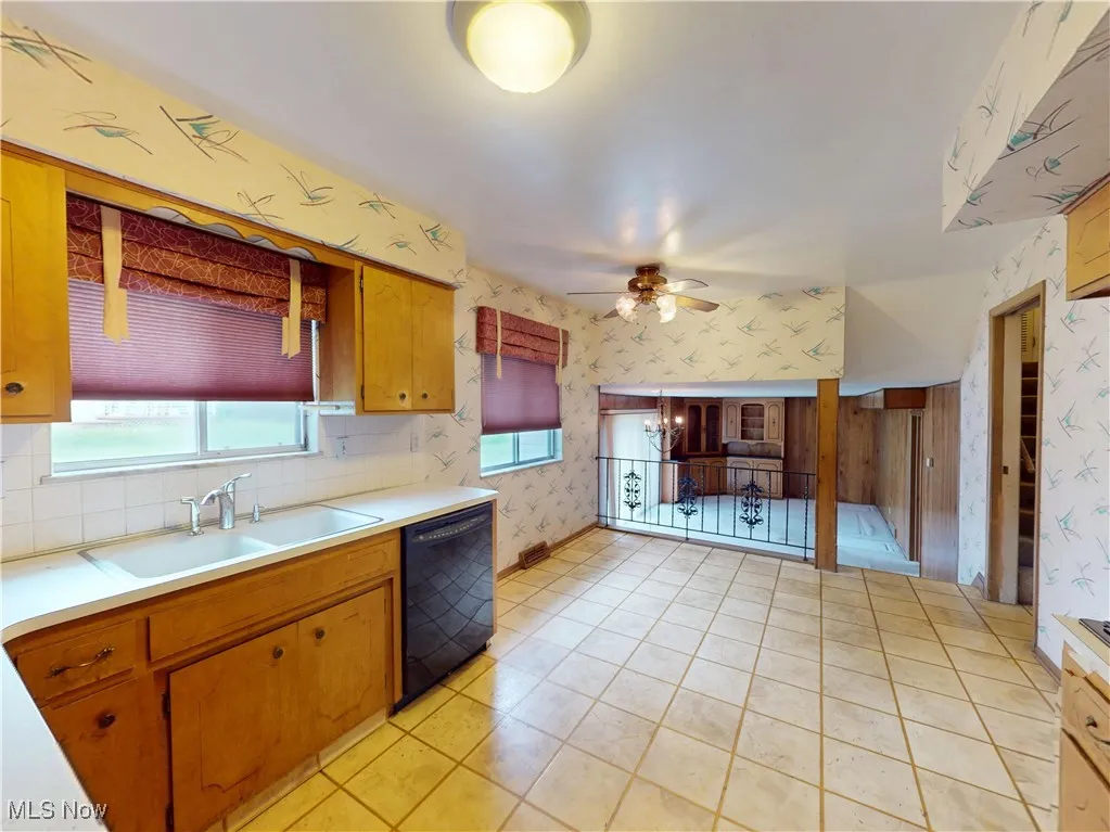 Kitchen featuring black dishwasher, wallpapered walls, a sink, light countertops, and ceiling fan