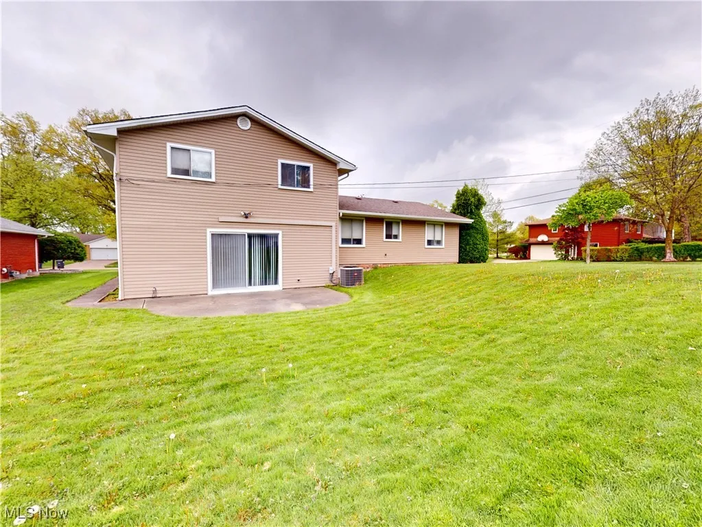 Rear view of house featuring a patio area, a lawn, and cooling unit