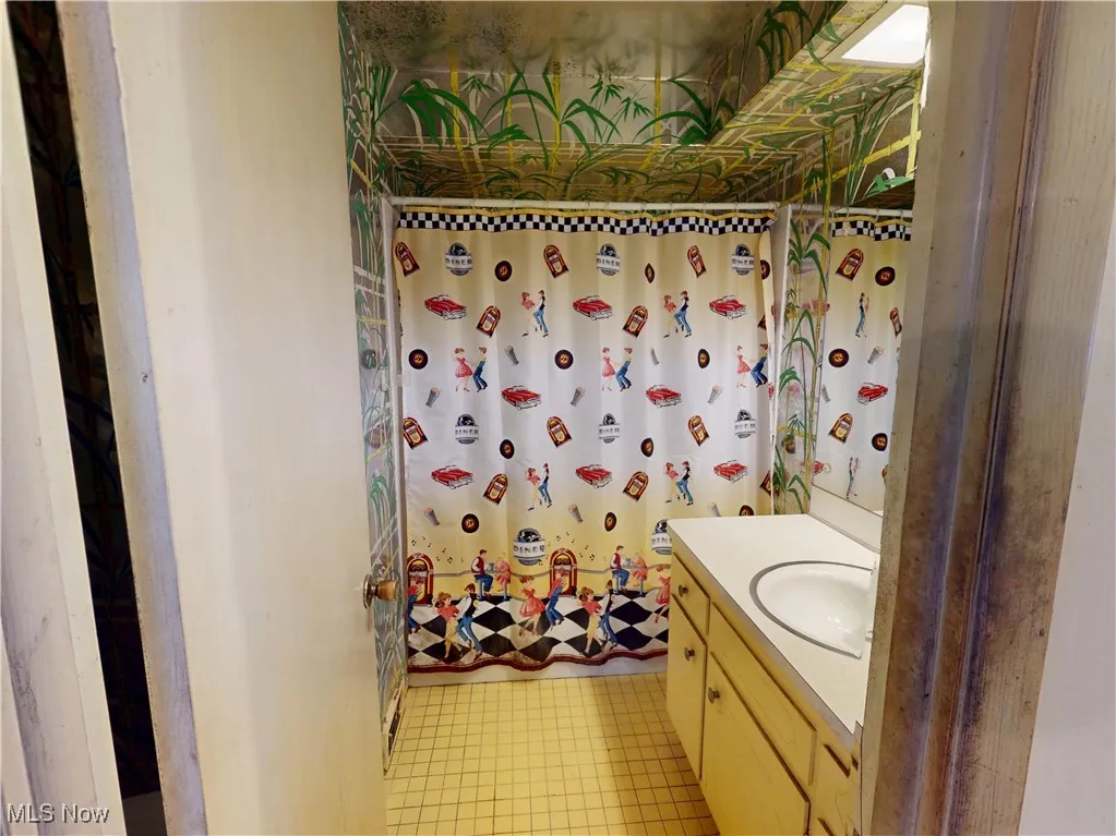 Full bathroom with tile patterned floors, a shower with shower curtain, and vanity