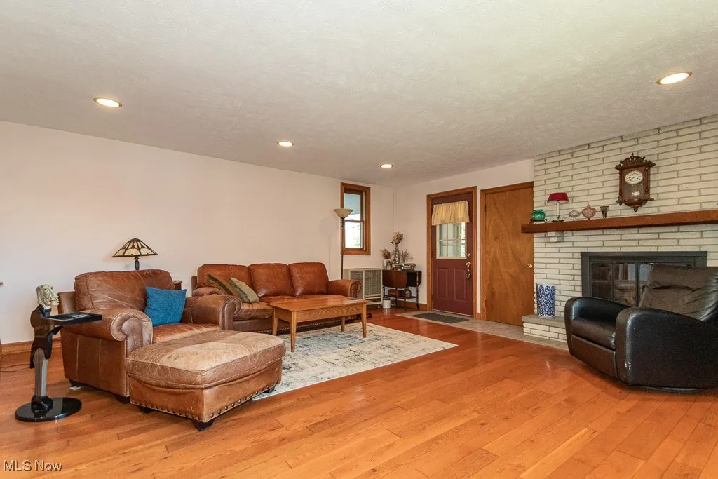 Living area featuring wood-type flooring, a fireplace, recessed lighting, and baseboards