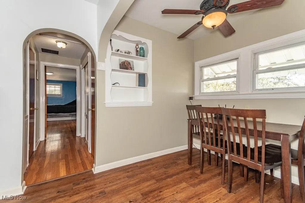 Dining room featuring arched walkways, wood finished floors, ceiling fan, and baseboards