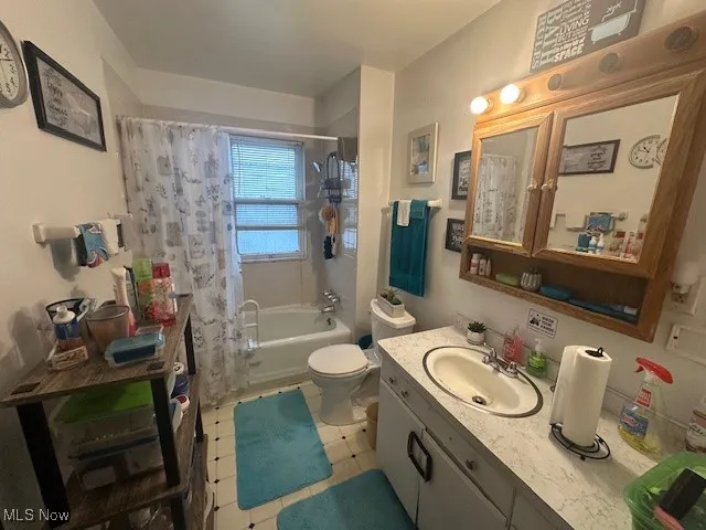 Bathroom with vanity, shower / bath combo, toilet, and tile patterned flooring