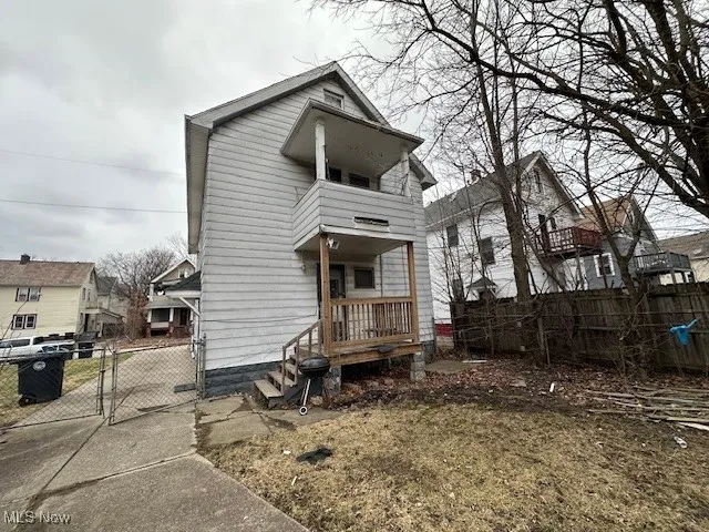 Back of house with a balcony, fence, and a gate