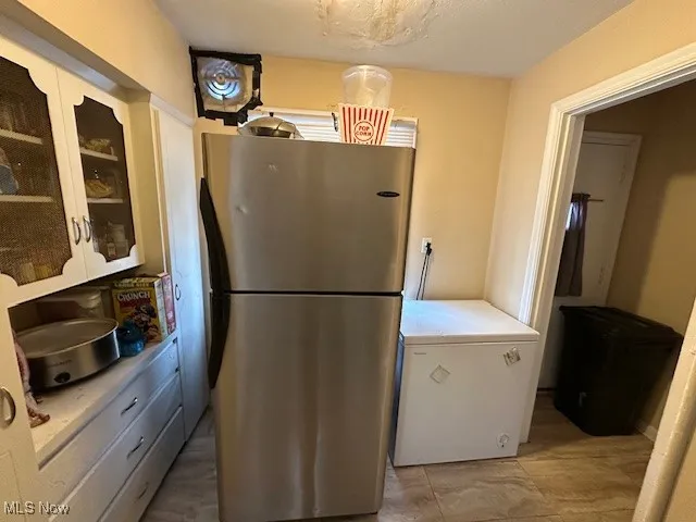 Kitchen with freestanding refrigerator, fridge, light countertops, and glass insert cabinets