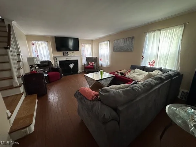 Living room with stairs, a fireplace with flush hearth, and hardwood / wood-style floors
