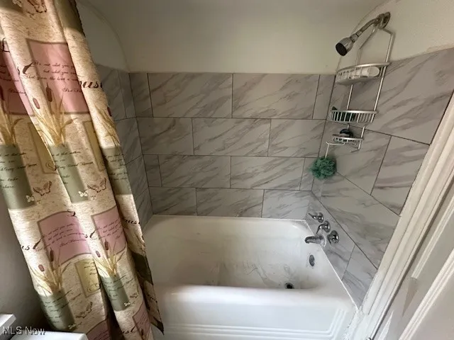 Full bathroom featuring shower / bath combo with shower curtain and toilet