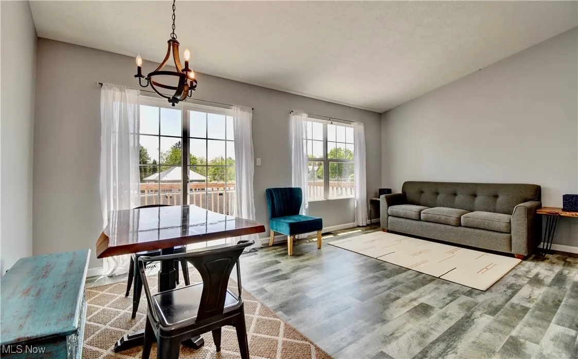 Living area featuring a chandelier, wood finished floors, baseboards, and vaulted ceiling