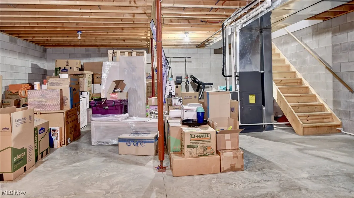 Unfinished below grade area featuring concrete block wall and stairs