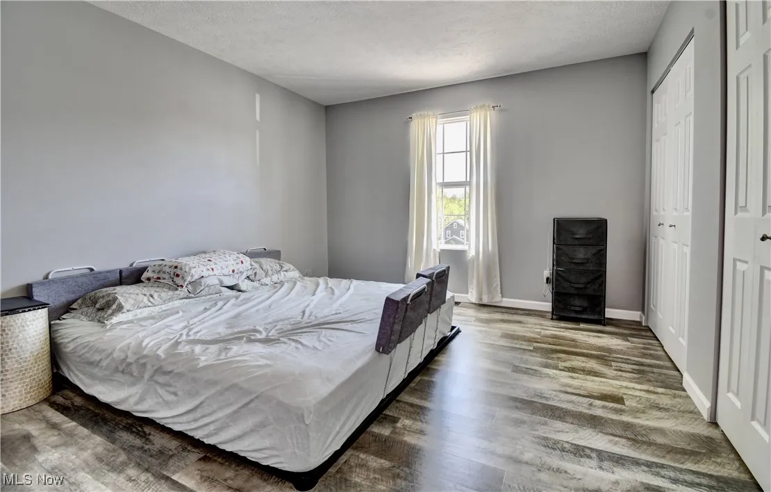 Bedroom with wood finished floors, a textured ceiling, and baseboards