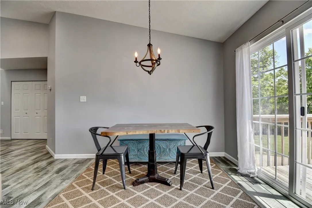 Dining space with wood finished floors, a chandelier, baseboards, breakfast area, and lofted ceiling