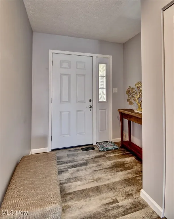 Foyer with baseboards and a textured ceiling
