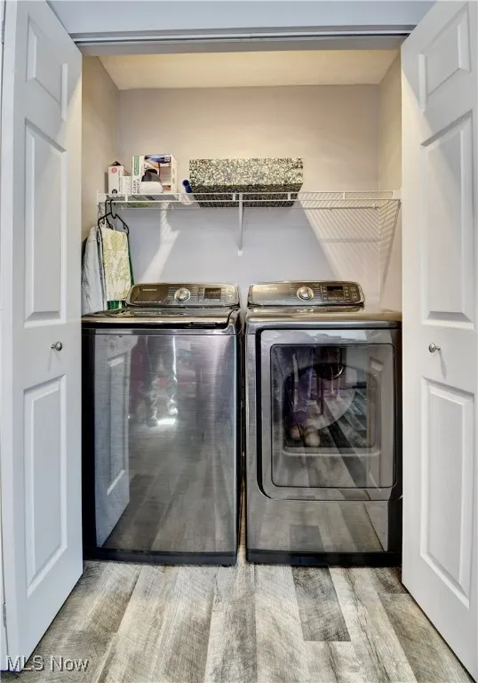 Washroom with washer and clothes dryer and wood finished floors