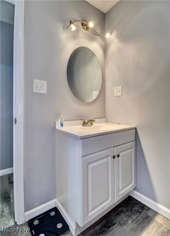 Bathroom featuring baseboards, wood finished floors, and vanity