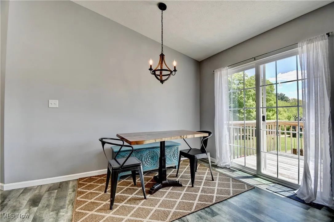 Dining room featuring vaulted ceiling, wood finished floors, a chandelier, and baseboards