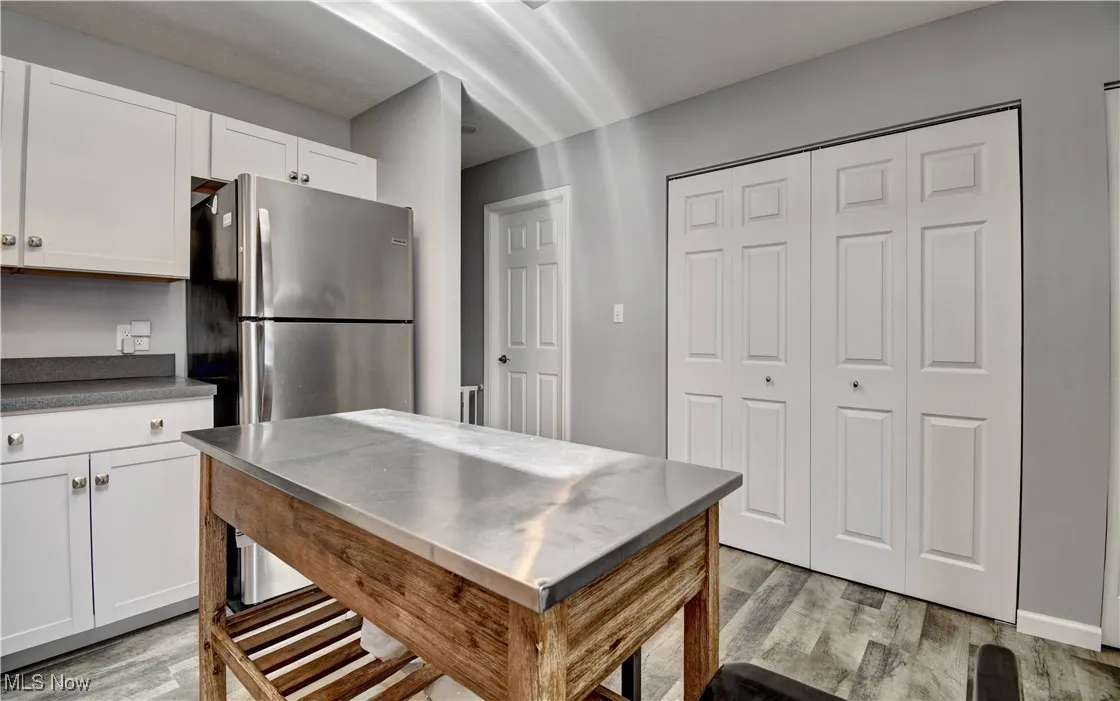 Kitchen with freestanding refrigerator, light wood-style flooring, and white cabinets
