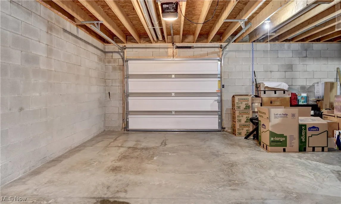 Garage featuring concrete block wall and a garage door opener