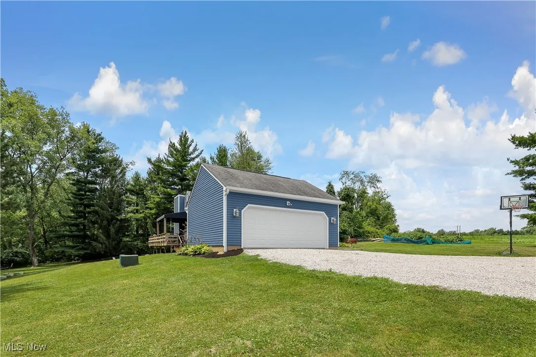 View of side of home with a yard and gravel driveway