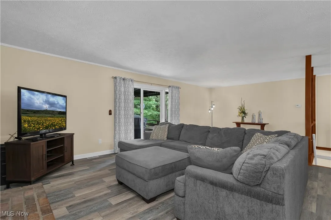 Living area with dark wood-type flooring, baseboards, and a textured ceiling
