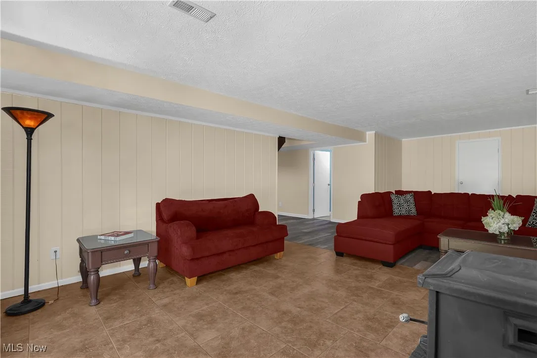 Living room with a textured ceiling, baseboards, and visible vents