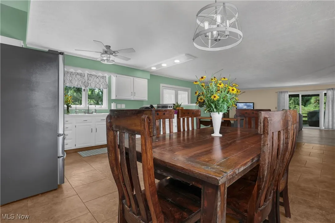 Dining area with recessed lighting, plenty of natural light, light tile patterned floors, and ceiling fan with notable chandelier