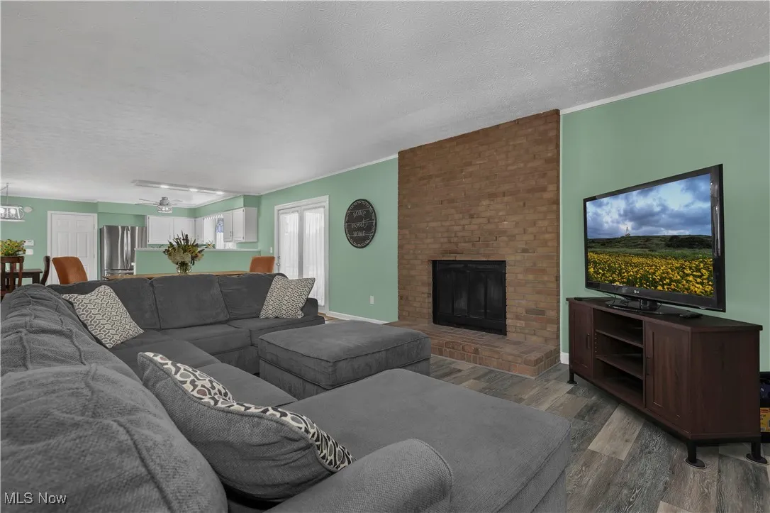Living room with a fireplace, a textured ceiling, an inviting chandelier, and wood finished floors
