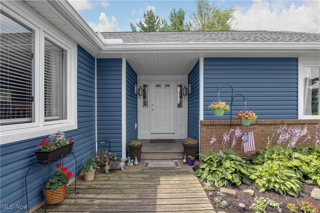Doorway to property featuring a shingled roof and brick siding