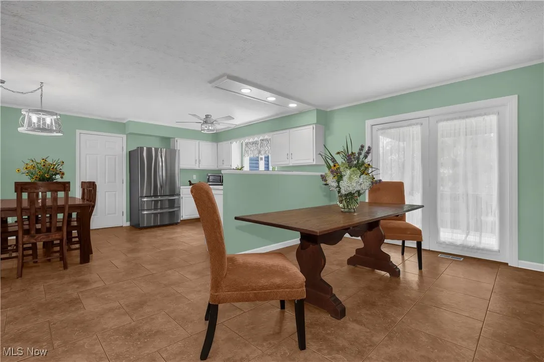Tiled dining space featuring recessed lighting, a textured ceiling, a ceiling fan, and ornamental molding