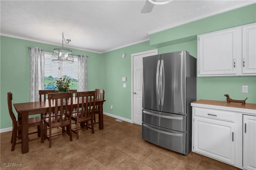 Dining area with a textured ceiling, crown molding, ceiling fan, and baseboards
