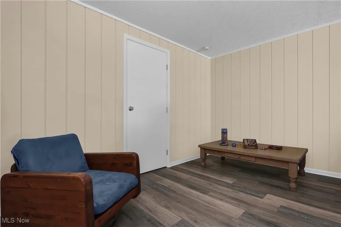 Sitting room with a textured ceiling, wood finished floors, baseboards, and ornamental molding
