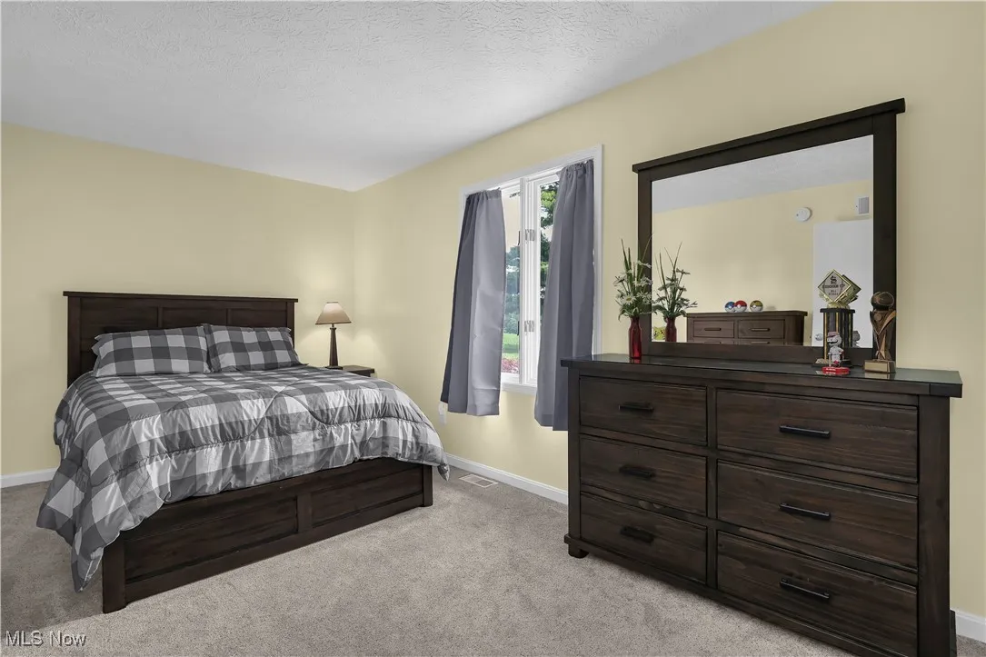 Carpeted bedroom featuring visible vents and baseboards