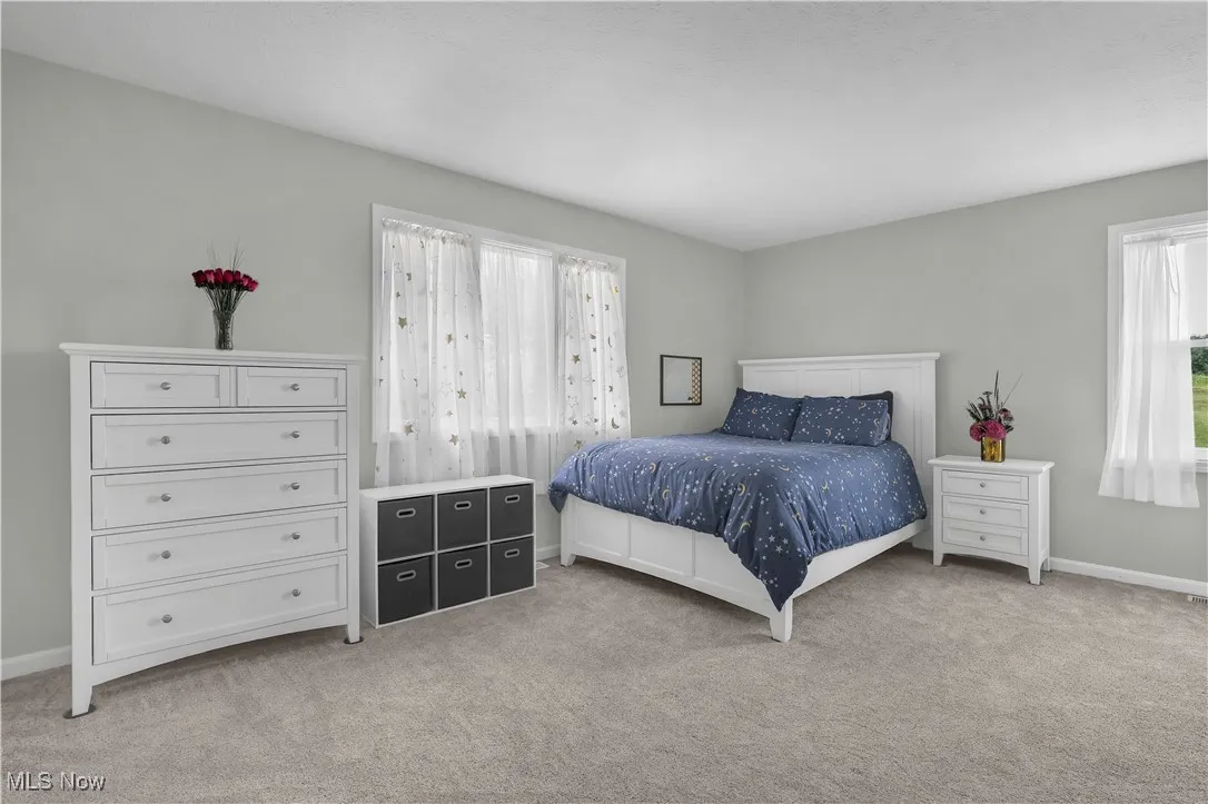 Bedroom with light colored carpet and baseboards