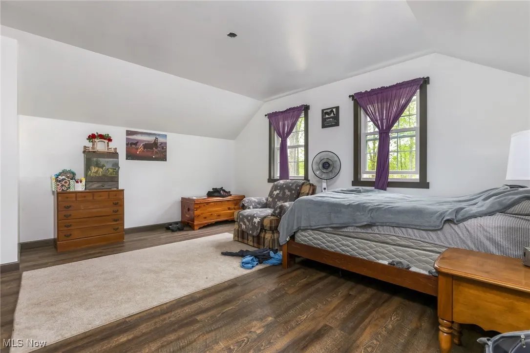 Bedroom with lofted ceiling, wood finished floors, and baseboards