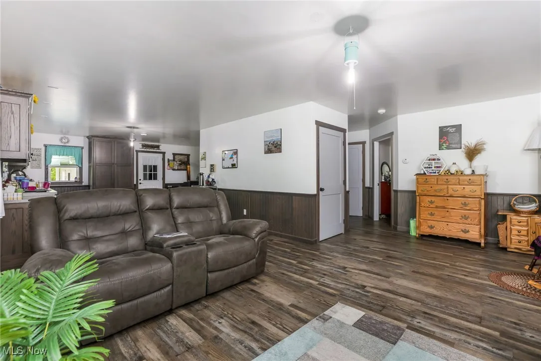 Living room with a wainscoted wall, dark wood-style floors, and wooden walls