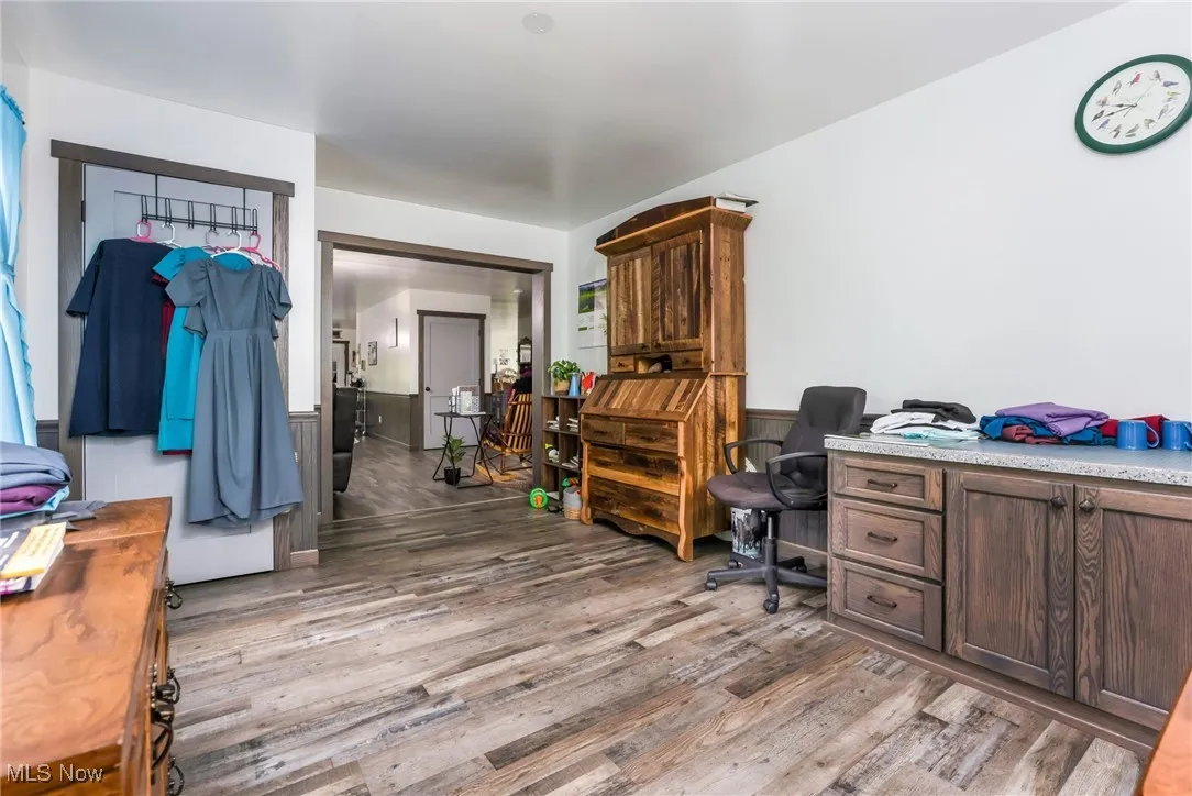 Home office with light wood-type flooring and a wainscoted wall