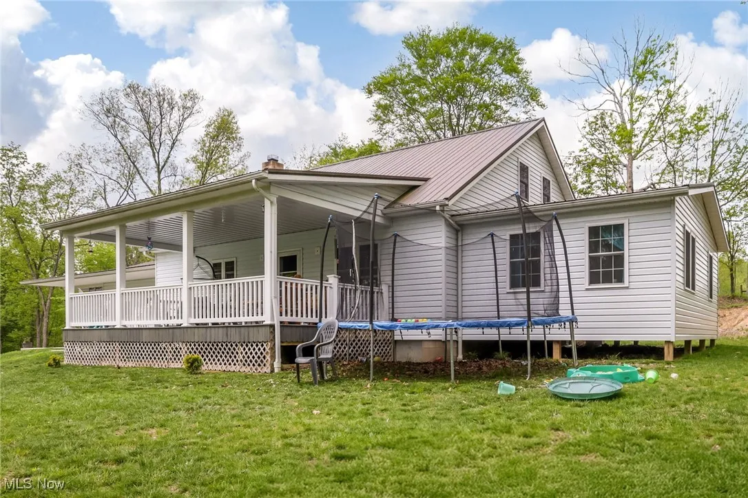 Back of house with a lawn, a trampoline, and metal roof