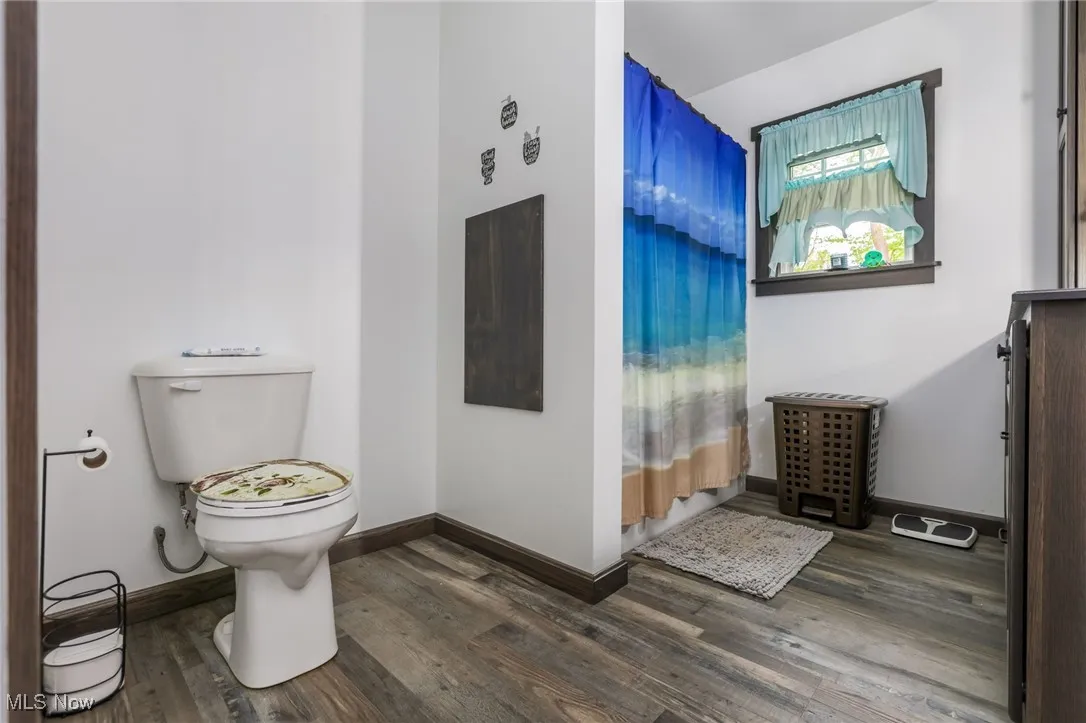 Bathroom with wood finished floors, toilet, and baseboards