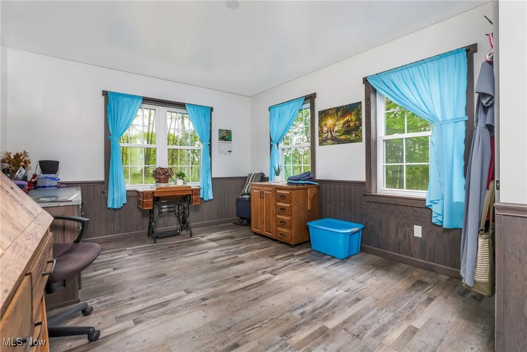 Home office with wainscoting, wood finished floors, plenty of natural light, and wood walls