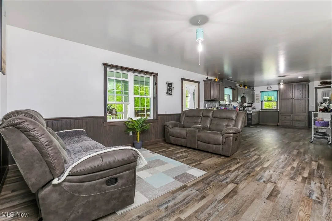 Living room with wainscoting, dark wood finished floors, and wooden walls