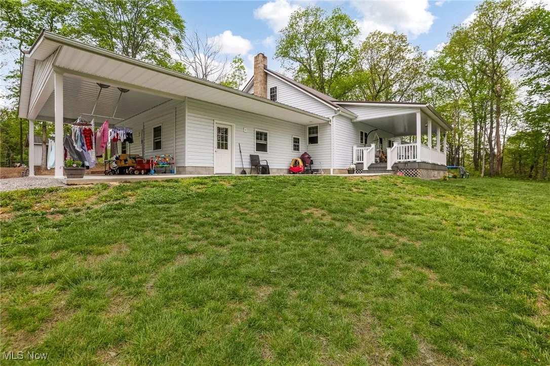 Rear view of property featuring a lawn, a chimney, and a patio