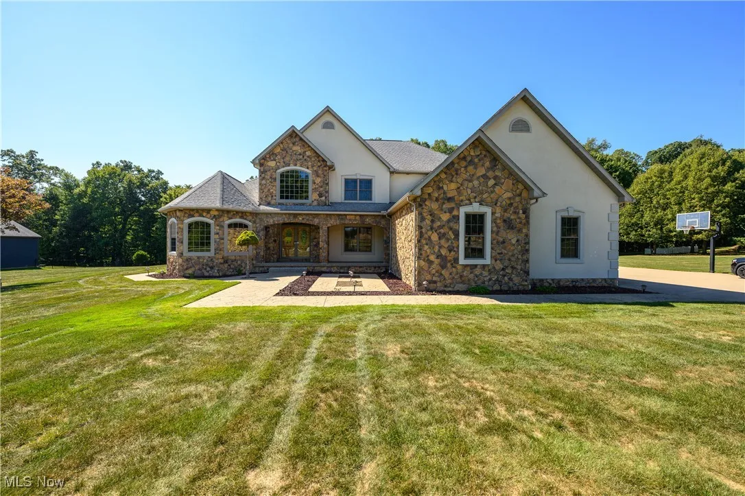 French provincial home with stone siding, stucco siding, and a front yard