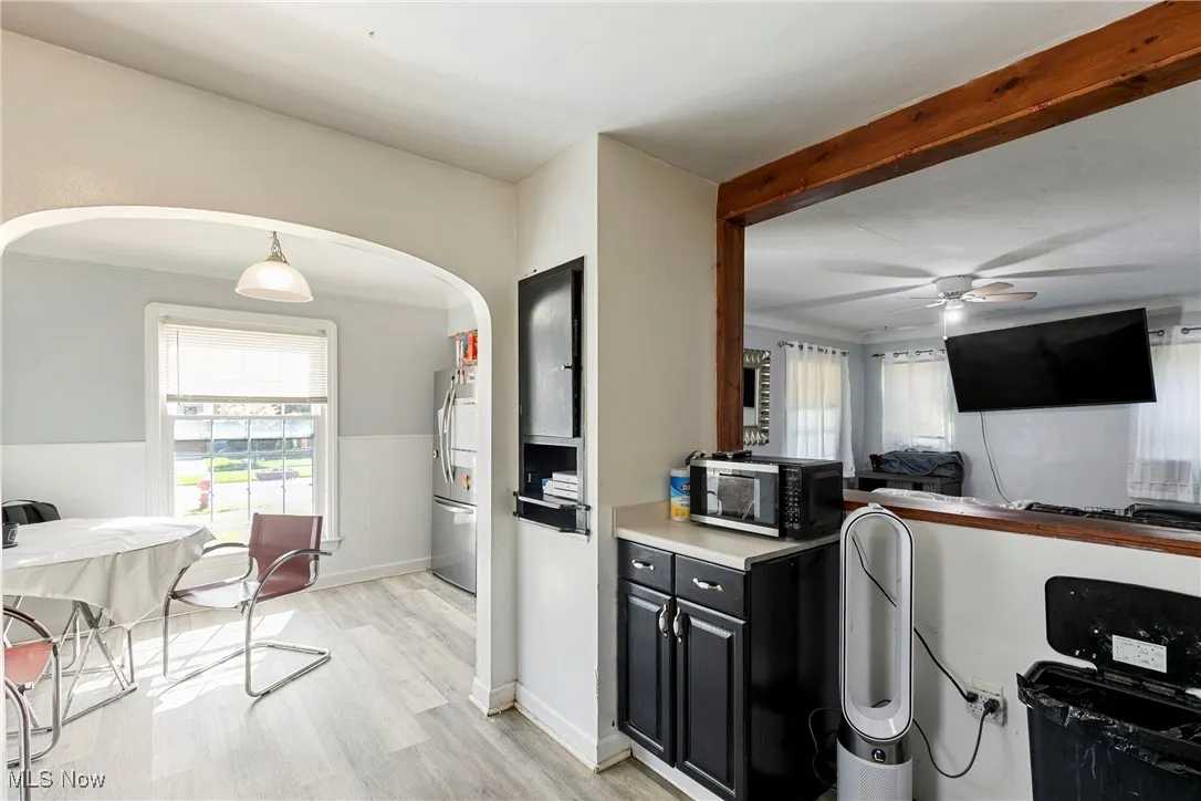 Kitchen featuring arched walkways, stainless steel fridge, ceiling fan, light wood finished floors, and dark cabinets