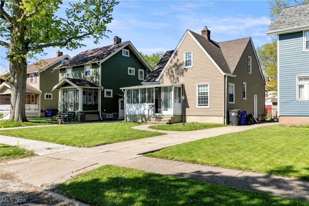View of front of property with a sunroom, entry steps, a front yard, a chimney, and a residential view
