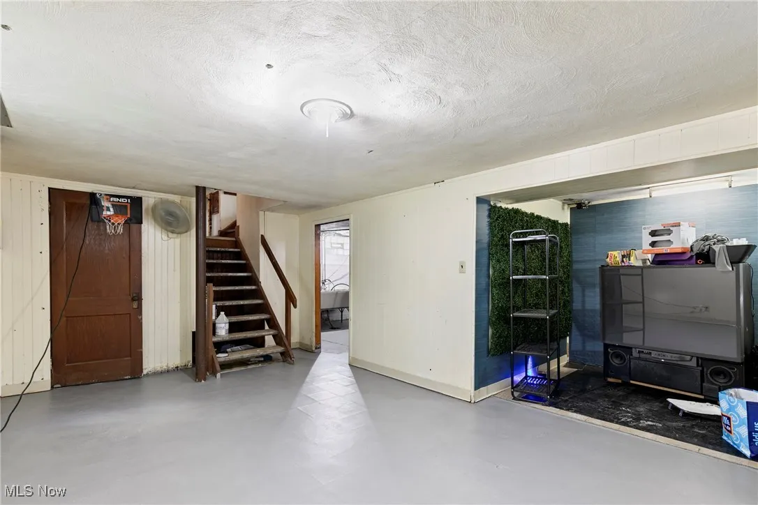Finished below grade area featuring stairway, a textured ceiling, and baseboards