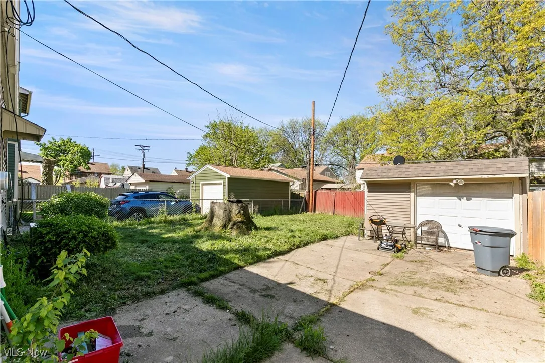 View of yard featuring fence, driveway, a garage, and an outbuilding