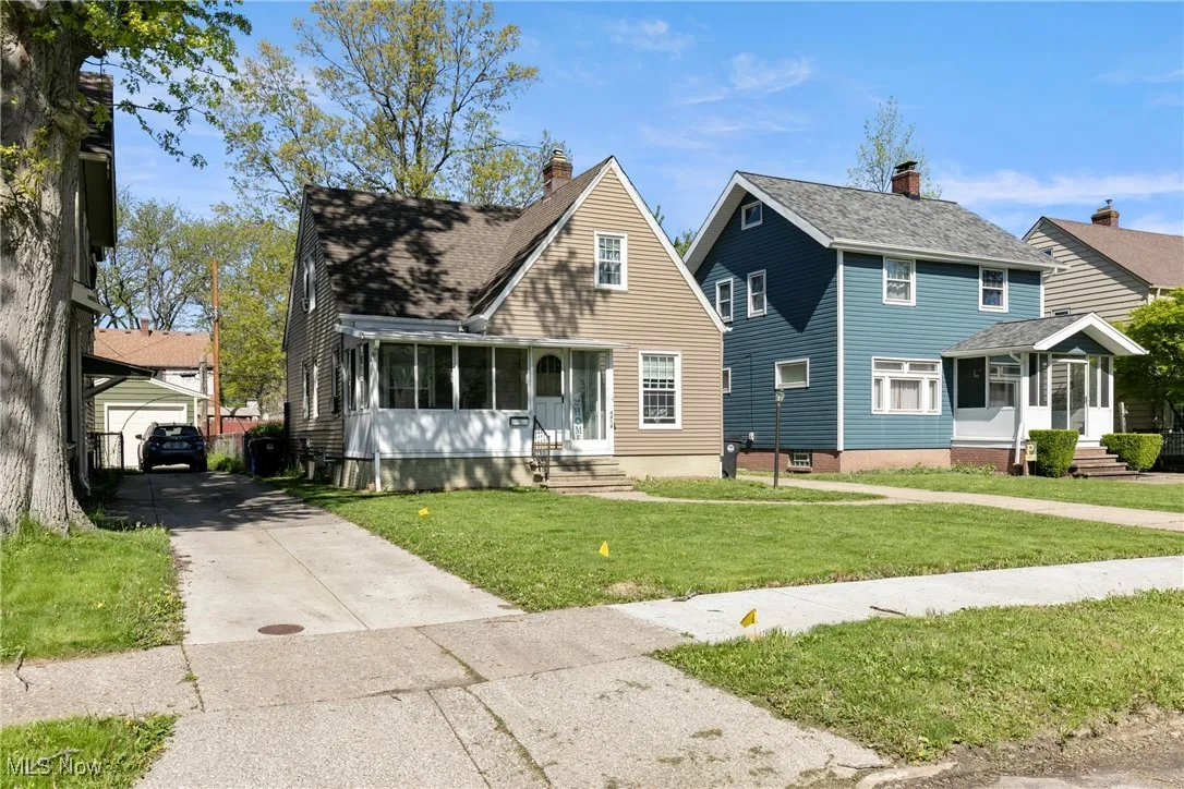 View of front facade featuring entry steps, concrete driveway, an outbuilding, a front lawn, and a sunroom