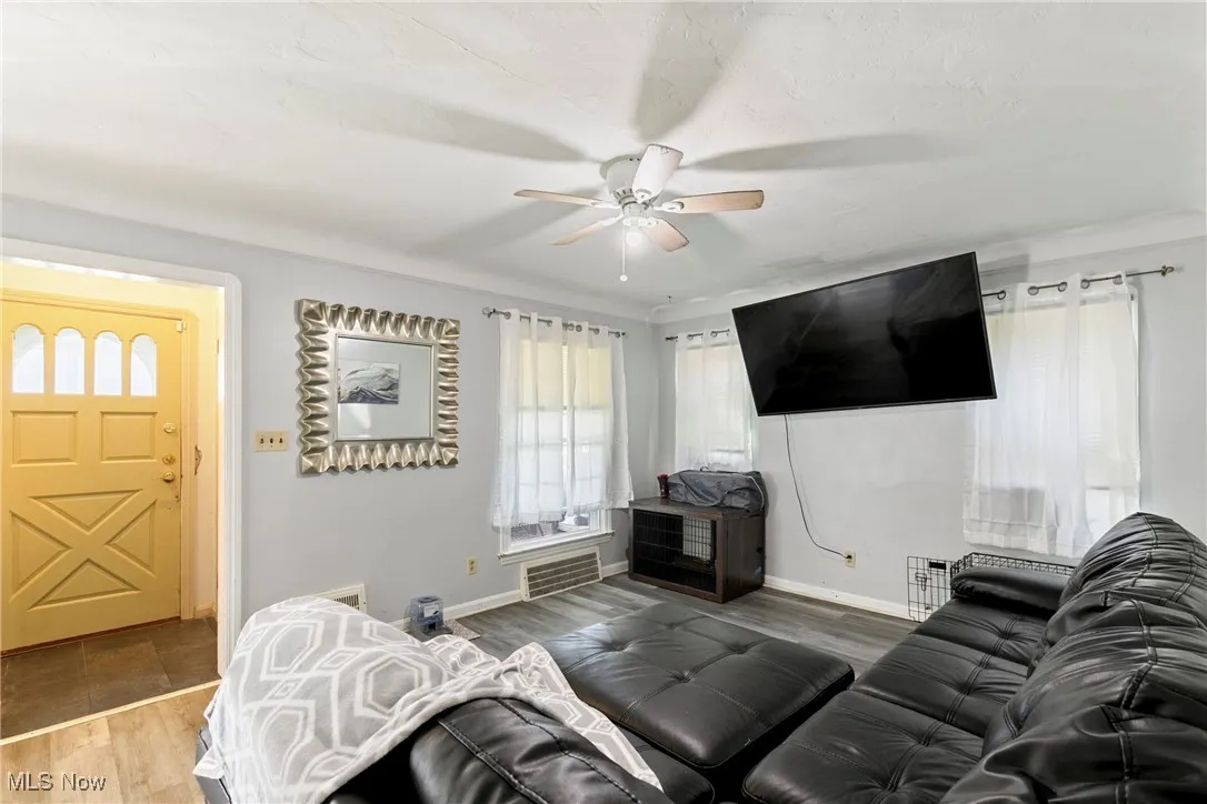 Living area with wood finished floors, ceiling fan, and baseboards