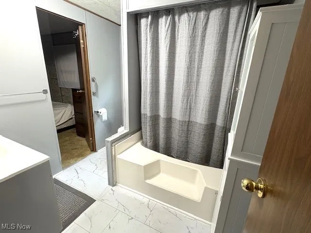 Full bathroom featuring marble finish flooring, a tub to relax in, ensuite bathroom, curtained shower, and vanity