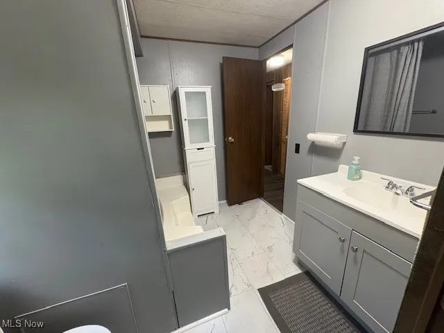 Bathroom featuring marble look tiles, vanity, and a textured ceiling
