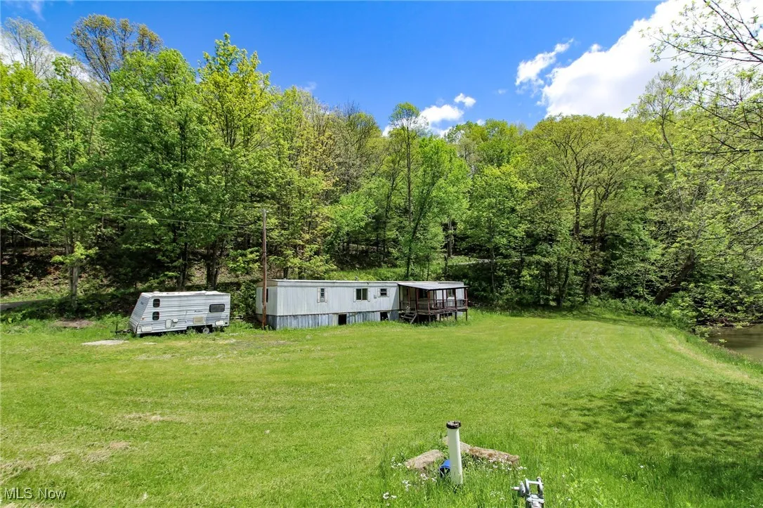 View of green lawn featuring an outdoor structure and a forest view